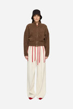 A woman wearing a brown fluffy bomber jacket.