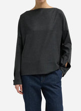 Person wearing a dark gray boatneck long-sleeve shirt on a light gray background
