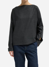 A person wearing a dark charcoal gray flannel wide-neck long-sleeve top shown against a light gray studio background.
