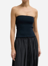 A model wearing a dark navy blue strapless ribbed knit tube top, shown from the neck down against a light gray studio background.