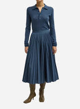 A blue pleated skirt that falls to mid calf length on a light grey background