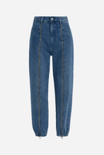 Blue jogger style jeans with zippers going down front of pant legs on a light grey background