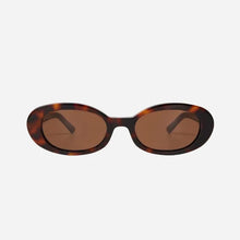 Sunglasses with tortoiseshell frame and brown lenses on a light grey background