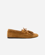 Brown suede loafer with tassels on a light grey background