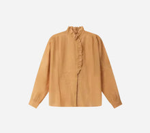 Beige blouse with orange undertones with ruffled details on the collar, on a light grey background