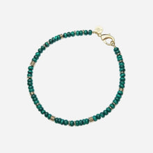 A beaded bracelet featuring round green malachite beads separated by small gold spacer beads, finished with a gold lobster clasp and a round gold brand tag.
