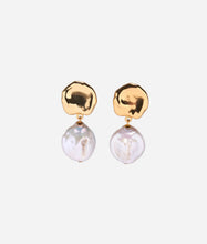 Gold earrings with pearl drops on a light grey background