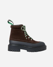 Brown boot with green laces and black platform sole on a light gray background