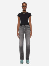 A model stands against a light gray studio background wearing a black short-sleeve t-shirt, gray high-waisted straight-leg jeans, and teal sneakers.