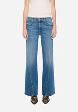 A model wearing a pair of medium-wash blue flare jeans, standing against a light grey studio background.