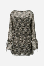 A sheer long-sleeve mini dress with a black and beige abstract textured pattern, featuring a smocked bodice, a matching fabric tie belt, and ruffled cuffs, shown against a light grey background