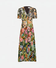 A short-sleeve V-neck maxi dress with an all-over dense floral print in green, pink, orange, yellow, and blue, shown against a solid off-white background.