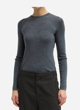 Person wearing a ribbed gray crewneck sweater on a light gray background