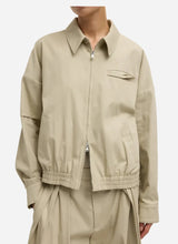 Beige zip up jacket with collar worn by a person on a light grey background