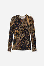 A long-sleeve crewneck top featuring an intricate gold paisley and floral pattern, presented flat against a light gray studio backdrop.