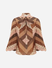 A long-sleeve blouse with a high collar and front tie, featuring a geometric patchwork pattern in shades of brown, beige, and dusty pink.